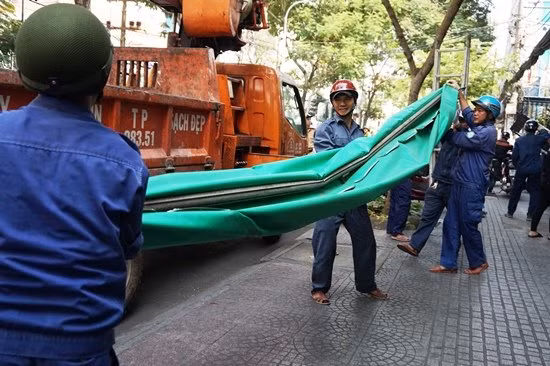 Nhân viên công ích quận 1 nhanh chóng tháo bỏ mái che di động, chuyển lên xe đặc dụng.