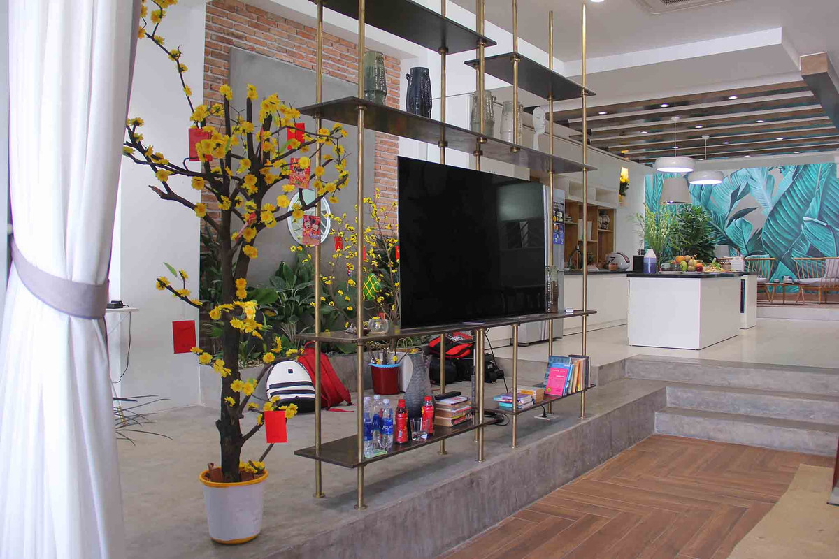 Căn nhà có 3 tầng, 1 trệt, rộng 300 m2. Phần nền không lót gạch, để nguyên chất liệu xi-măng. Mảng tường được ốp gạch nung, mang lại cảm giác mộc mạc.