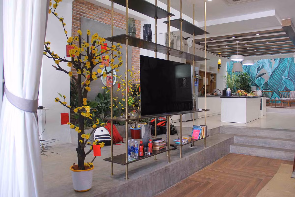 Căn nhà có 3 tầng, 1 trệt, rộng 300 m2. Phần nền không lót gạch, để nguyên chất liệu xi-măng. Mảng tường được ốp gạch nung, mang lại cảm giác mộc mạc.