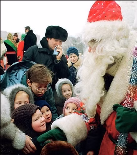 Nhiều trẻ em vây quanh ông già Noel.