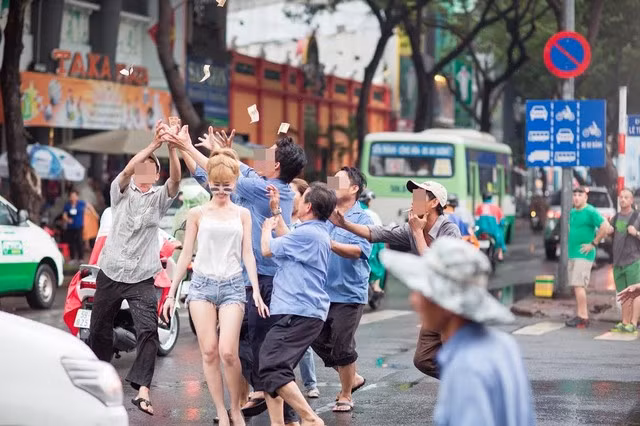 Cô gái mặc áo hai dây, quần soóc khoe chân dài, đeo kính mát cầm một cọc tiền đi trên vỉa hè, đến mép đường thì vung tiền, để đám người đàn ông xung quanh xúm lại, chạy theo lụm nhặt. Cảnh tượng khiến nhiều người đi đường phải "há hốc mồm" kinh ngạc.
