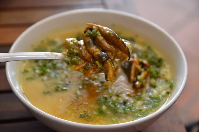 Cháo lươn Nghệ An không chỉ là món ăn ưa thích của người dân xứ Nghệ, mà của cả du khách trong và ngoài nước. Cháo được nấu từ nước ninh với xương sống lươn giã dập, có vị ngọt thanh. Khi ăn, cho thêm thịt lươn xào với nghệ, ớt và hành tăm thơm đậm, cay nồng tạo nên hương vị "không nơi mô có được". Ảnh: Thedropoutdiaries.