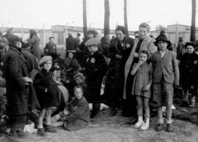 Những người phụ nữ và những đứa trẻ đứng chờ bên ngoài một lò thiêu.