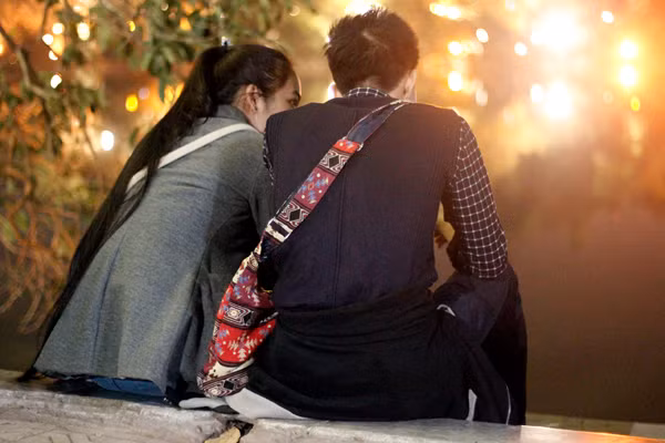 Hai bạn trẻ ngồi bên nhau giữa tiết trời lạnh dưới 20 độ C trên Bờ Hồ để nghe hát vì không bon chen được do lượng người quá đông.