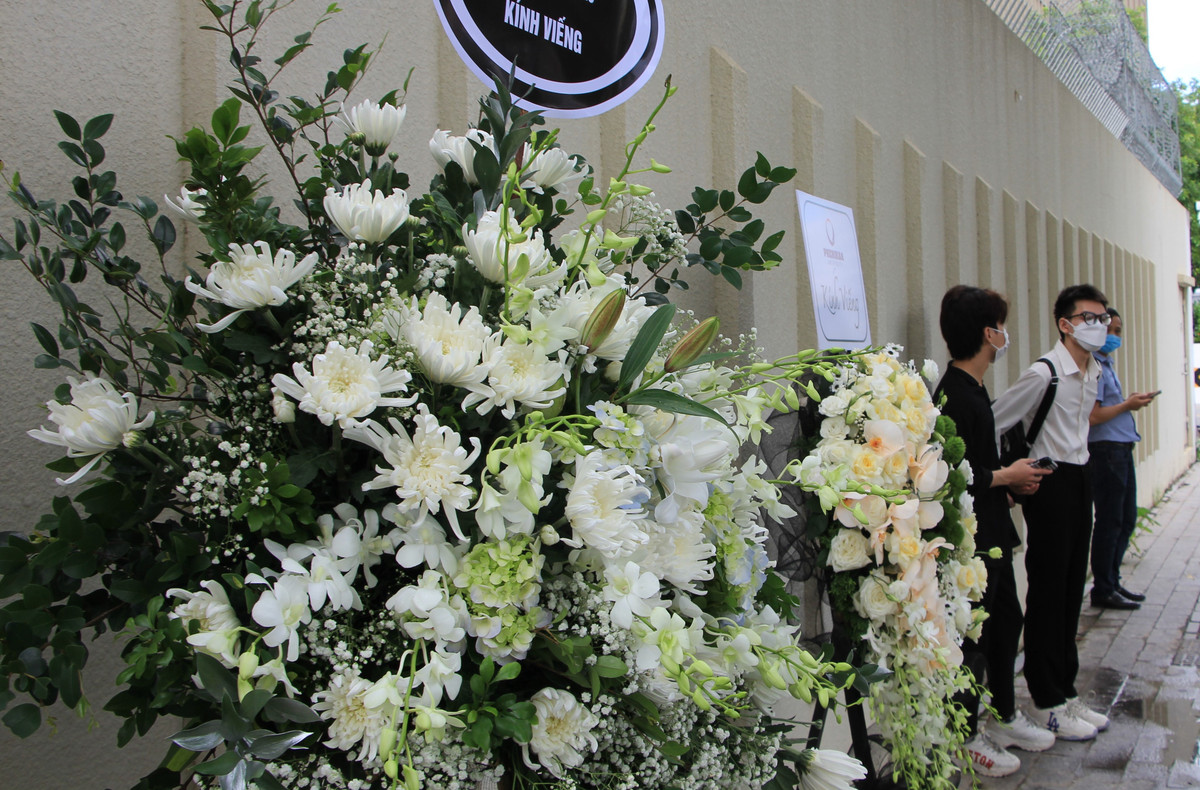 Nhiều người mang theo hoa tươi, mặc đồ đen đứng xếp hàng bên ngoài Đại sứ quán.