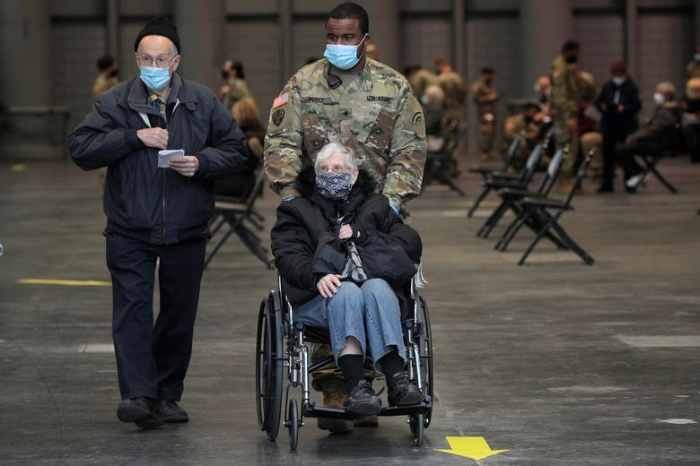 Ông Fred Walter và vợ, bà Joa, được một người lính hỗ trợ sau khi được tiêm vắc xin phòng COVID-19.