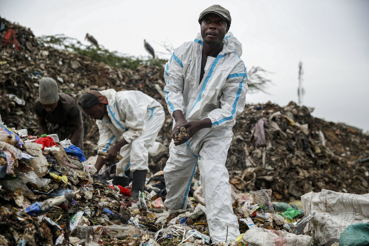 Duncan Wanjohi (phải) và Kelvin Kimani (giữa), tìm kiếm những vật liệu có thể tái chế tại Dandora, bãi rác lớn nhất ở thủ đô Nairobi của Kenya, ngày 28/3/2021. Ảnh: AP.