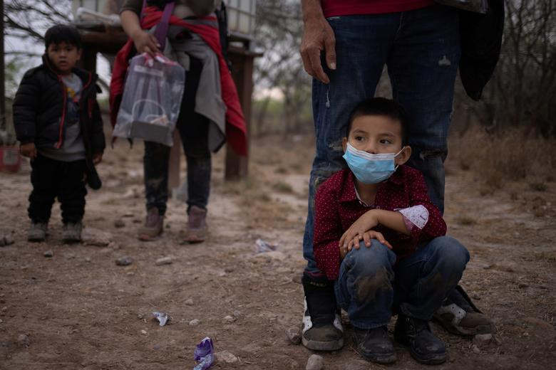 Jonathan, 6 tuổi, đến từ Honduras, ngồi chờ cùng cha và những người di cư khác sau khi vượt sông Rio Grande từ Mexico vào Mỹ hôm 14/3.