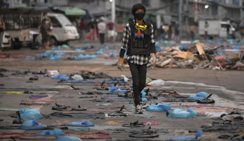 Người biểu tình đi trên con đường đầy túi nước vốn được sử dụng để đối phó hơi cay của lực lượng an ninh Myanmar, tại Yangon, ngày 14/3.