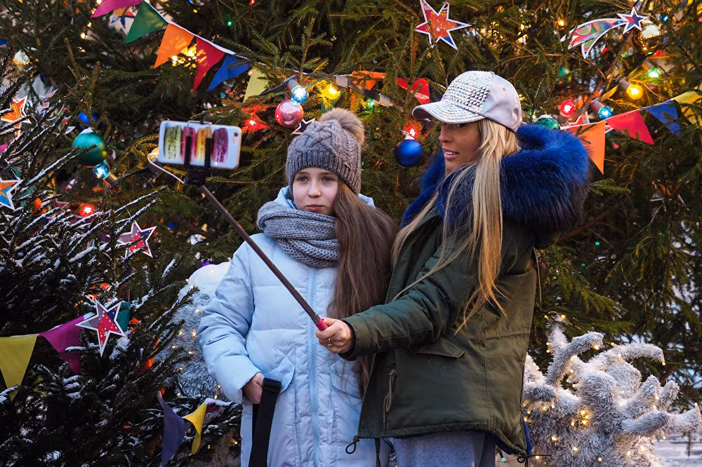 Hai cô gái chụp ảnh “tự sướng” cạnh cây thông Noel ở Moscow. Ảnh Sputnik
