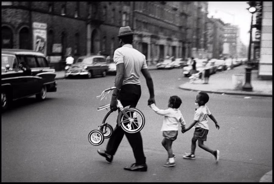 Người đàn ông dắt hai em nhỏ qua đường ở Harlem, New York, năm 1963.