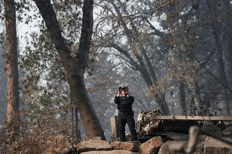 Một nhân viên Mật vụ Mỹ đứng quan sát khi Tổng thống Trump thăm thị trấn Paradise sau thảm họa cháy rừng khủng khiếp. Ảnh: Reuters.