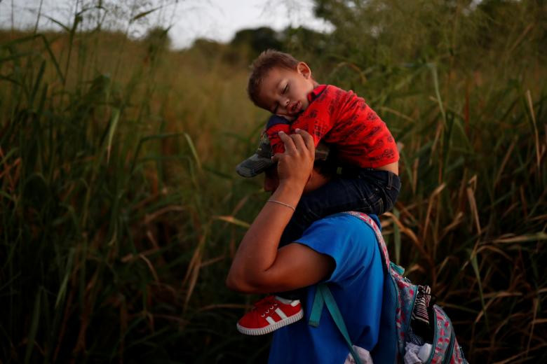 Oscar Martinez, một di dân 37 tuổi đến từ Honduras, cõng con trai của anh, Dilan 3 tuổi, khi đi bộ dọc con đường dẫn tới Huixtla, gần Tapachula, Mexico, ngày 31/10.