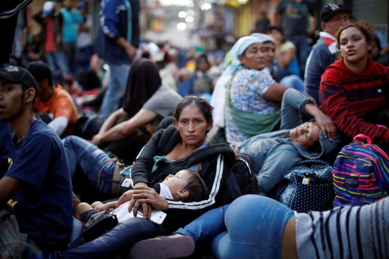 Hãng thông tấn Reuters đăng tải loạt ảnh ghi lại những gương mặt trẻ di cư cùng gia đình trên hành trình vượt biên đến "miền đất hứa" Mỹ. Ảnh: Người phụ nữ bế con trai của cô trong lúc chờ tại Tecun Uman, Guatemala, hôm 2/11 để được vào Mexico, tiếp tục hành trình tới Mỹ. (Nguồn ảnh: Reuters)