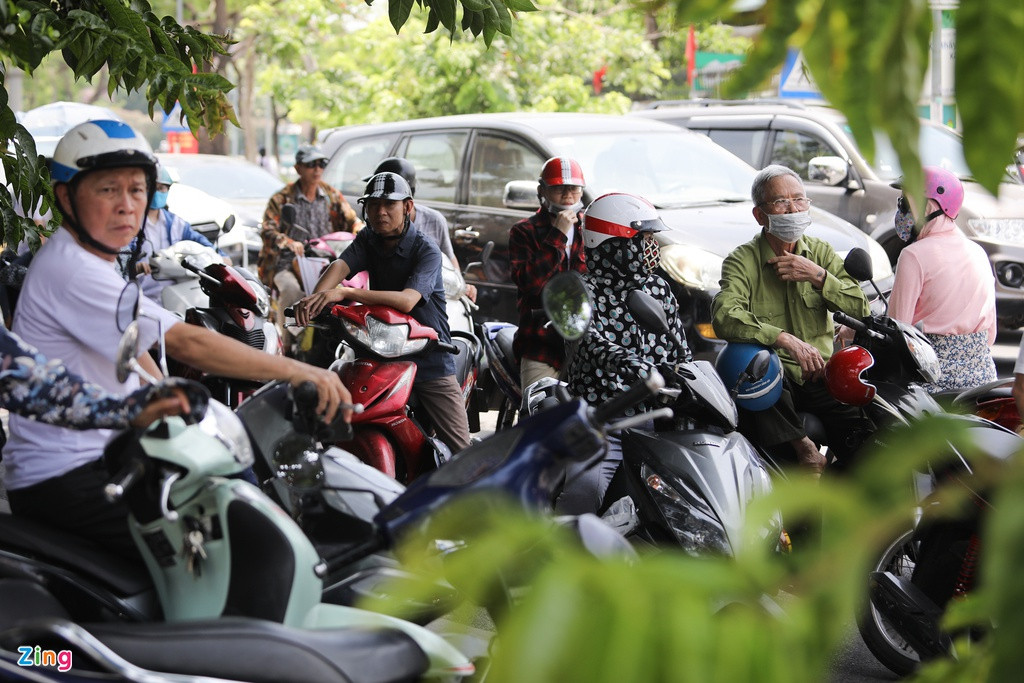 Tại trường THCS Dịch Vọng (quận Cầu Giấy, Hà Nội), phụ huynh xếp hàng dài đợi đón con lúc 11h ngày 21/5. Nhiều người đỗ xe xuống lòng đường, bên dưới khu vực có bóng cây để tránh nắng.