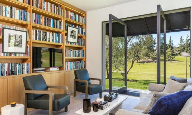 Khu vực đọc sách trang nhã với kệ sách bằng gỗ cỡ lớn cùng cánh cửa xoay dẫn ra không gian sân vườn.