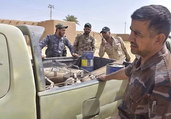 Các thành viên của lực lượng Iraq vây quanh một chiếc xe quân sự... Ảnh: FNA.