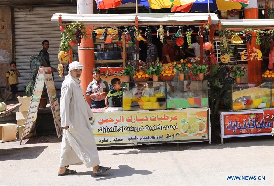 Người đàn ông đi qua một cửa hàng bán nước ép trái cây ở Tây Mosul ngày 27/5. Ảnh: THX.