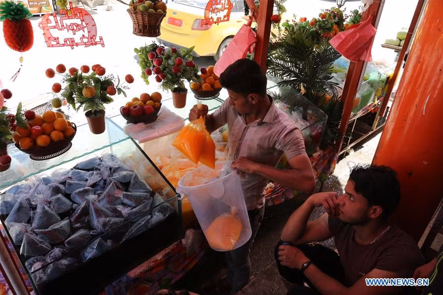 Người bán hàng đặt những túi nước ép trái cây vào xô tại cửa hàng ở khu vực mới được giải phóng phía tây thành phố Mosul hôm 27/5. Ảnh: THX.