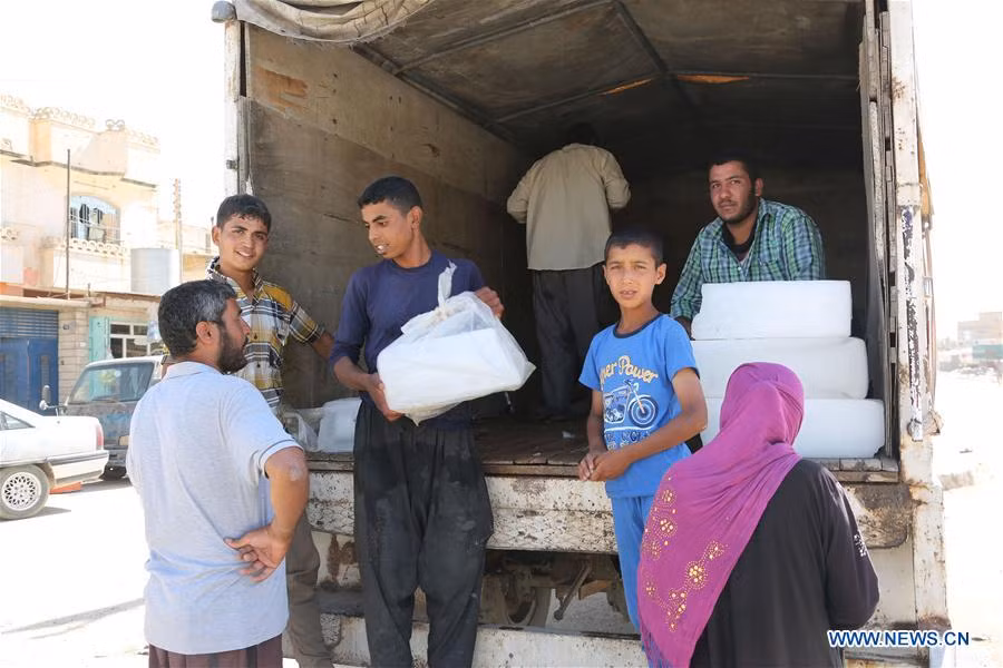 Người dân Iraq mang những tảng đá lạnh xuống xe hôm 27/5. Ảnh: THX.