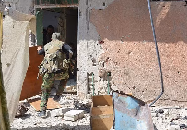 Một binh sĩ rút vào ngôi nhà bị hư hại trong chiến tranh. Ảnh: FNA.