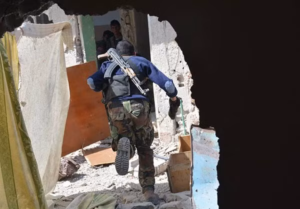 Một binh sĩ chạy vội vào trong một ngôi nhà ở Al-Qaboun. Ảnh: FNA.