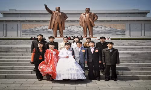 Cô dâu chú rể chụp ảnh cùng người thân trước bức tượng cố lãnh tụ Kim Il-sung và cố Chủ tịch Kim Jong-il ở thủ đô Bình Nhưỡng ngày 10/4/2013.
