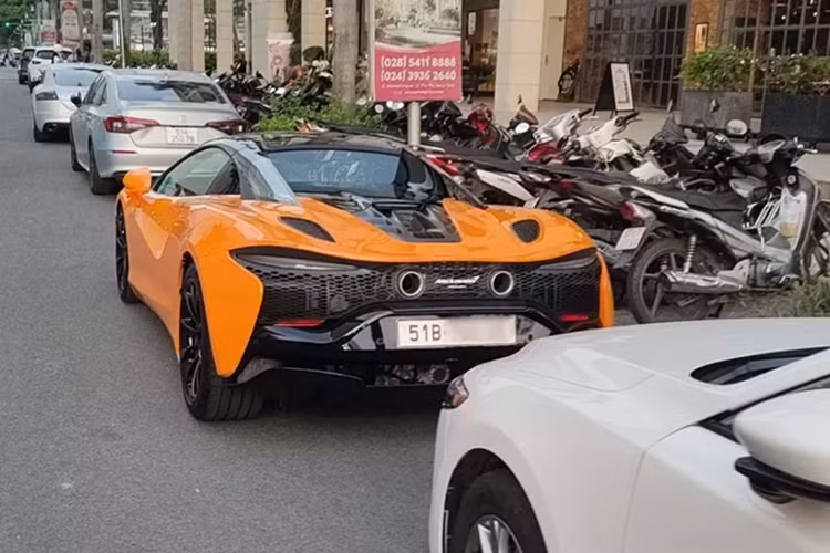 Hai chiếc siêu xe mui trần McLaren Artura Spider xuất hiện trước đó có màu tím và đen, còn xe này có màu cam với điểm nhấn là bộ mâm đa chấu và nhiều chi tiết ở ngoại thất sơn đen.