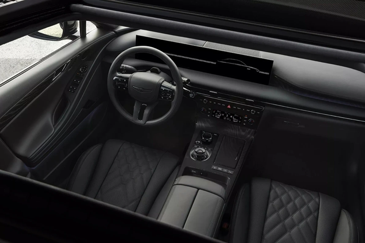 Khoang lái của Genesis G80 Black cũng lấy màu đen làm chủ đạo. Các chi tiết như cần số, núm chọn chế độ lái, bệ cửa, loa, logo hãng hay ghế da chần bông đều được phủ màu đen. Bảng táp-lô, bệ trung tâm và tapi cửa có chèn gỗ Black Ash. Phía sau vô lăng là cụm màn hình kích thước 27 inch, hiển thị ảnh động chào mừng và tạm biệt độc quyền.