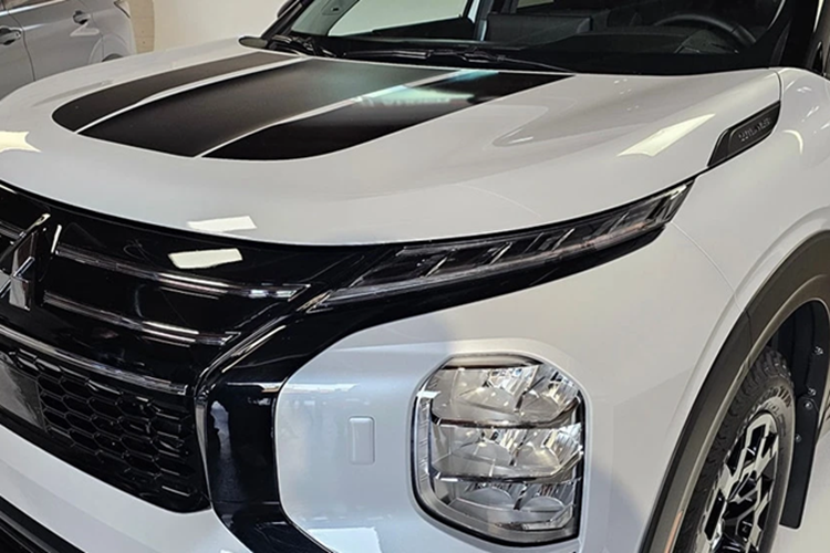 Nhiều chi tiết ngoại thất của mẫu xe SUV Mitsubishi Outlander Trail Edition này được sơn tối màu, tương tự biến thể Black Edition đang được phân phối tại Mỹ. Nắp capo cũng được dán các họa tiết màu đen.
