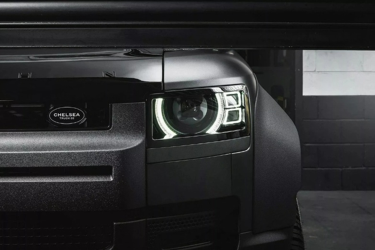 Bên cạnh đó, cụm đèn pha trước cũng được thiết kế lại mang phong cách sắc sảo hơn. Biểu tượng thương hiệu Land Rover ở đầu xe được thay thế bằng logo của Chelsea Truck Co., trong khi tên hãng độ Kahn Design được dập nổi trên nắp ca-pô, nhấn mạnh dấu ấn cá nhân hóa.