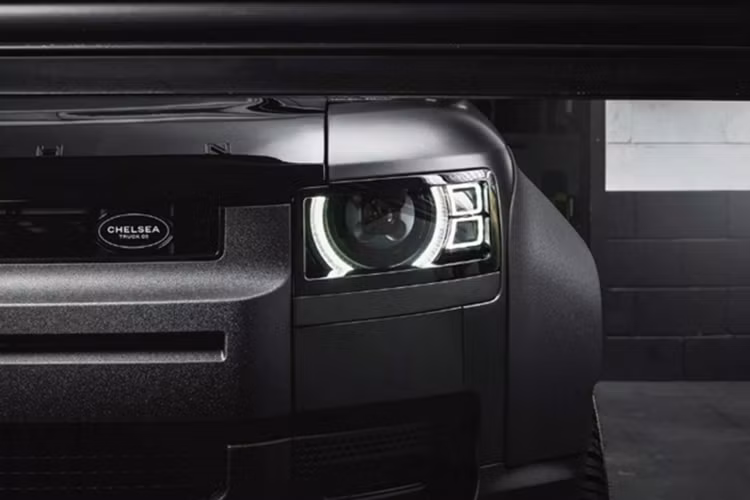 Bên cạnh đó, cụm đèn pha trước cũng được thiết kế lại mang phong cách sắc sảo hơn. Biểu tượng thương hiệu Land Rover ở đầu xe được thay thế bằng logo của Chelsea Truck Co., trong khi tên hãng độ Kahn Design được dập nổi trên nắp ca-pô, nhấn mạnh dấu ấn cá nhân hóa.