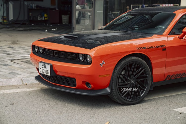 Chiếc Dodge Challenger tại Hà Nội trong bài thuộc thế hệ thứ ba, ra mắt từ năm 2008 nhưng thuộc bản nâng cấp của năm 2020. Xe nổi bật với lớp sơn màu cam rực rỡ, kết hợp các chi tiết màu đen tạo điểm nhấn. Phần đầu xe gây ấn tượng với mặt ca-lăng sơn đen, huy hiệu Challenger và GT cùng tông màu nên khá kín đáo. 