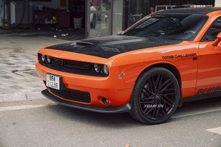 Chiếc Dodge Challenger tại Hà Nội trong bài thuộc thế hệ thứ ba, ra mắt từ năm 2008 nhưng thuộc bản nâng cấp của năm 2020. Xe nổi bật với lớp sơn màu cam rực rỡ, kết hợp các chi tiết màu đen tạo điểm nhấn. Phần đầu xe gây ấn tượng với mặt ca-lăng sơn đen, huy hiệu Challenger và GT cùng tông màu nên khá kín đáo. 