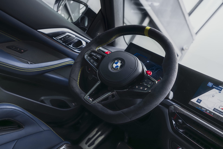 Nội thất của M4 CS Edition VR46 với ghế M Carbon bọc da Merino màu Đen/Xanh Đêm - Black/Night Blue Merino, điểm nhấn bằng chất liệu Alcantara màu vàng - Sao Paulo Yellow ở phần vai, cùng đường chỉ khâu vàng trên vô lăng và một dấu mốc vàng tại vị trí 12 giờ.