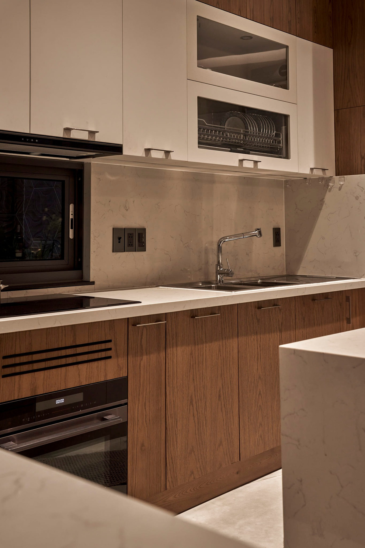 Bếp ngăn nắp, hiện đại với gam màu trắng và vàng gỗ. Phần cửa không có gờ để tiện cho việc vệ sinh, lau dọn.