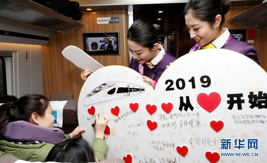 Trến chuyến tàu cao tốc từ Thượng Hải đến Bắc Kinh, Trung Quốc, hôm 30/12, nhân viên phục vụ tổ chức cho hành khách viết lời cầu chúc năm mới. Tấm biển trong ảnh đề dòng chữ (lớn): "Năm 2019 khởi đầu từ trái tim". Ảnh: Tân Hoa xã.