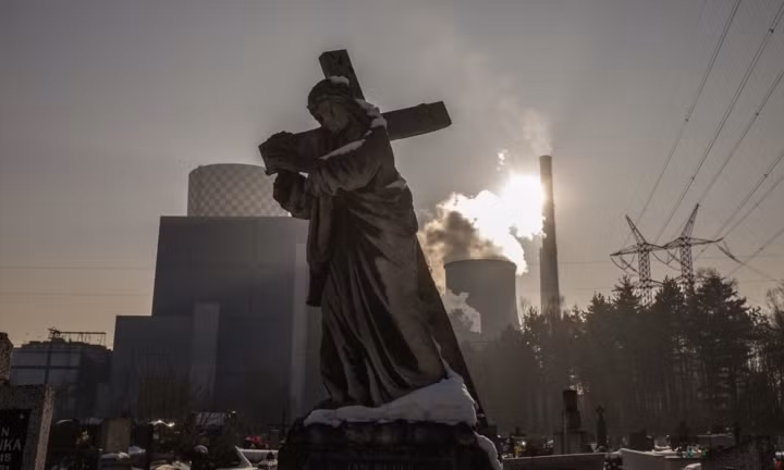 Bức tượng Chúa cùng cây thánh giá gần một nhà máy điện sử dụng than đá.