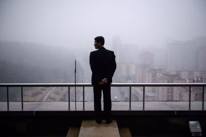 Một người đàn ông đứng trên tầng cao nhất của Khải Hoàn Môn, quan sát khung cảnh Bình Nhưỡng.