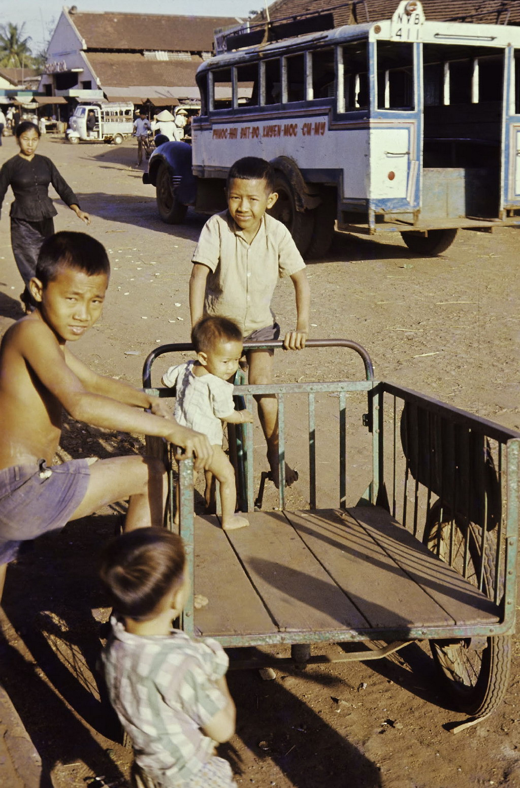 Trẻ em chơi đùa trên chiếc xe thồ bên ngoài chợ Đất Đỏ. Ảnh: Culturalspot.org.