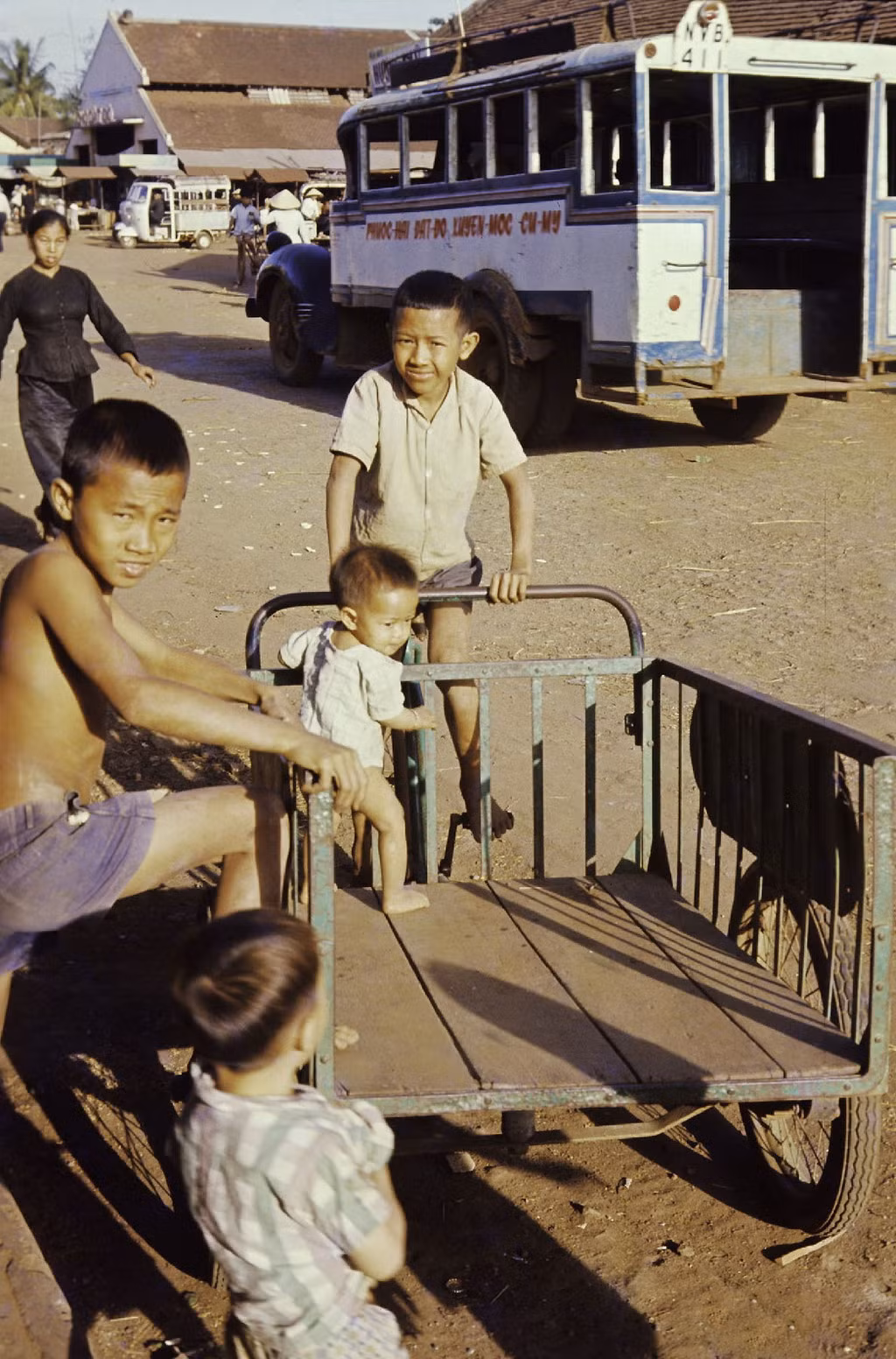 Trẻ em chơi đùa trên chiếc xe thồ bên ngoài chợ Đất Đỏ. Ảnh: Culturalspot.org.