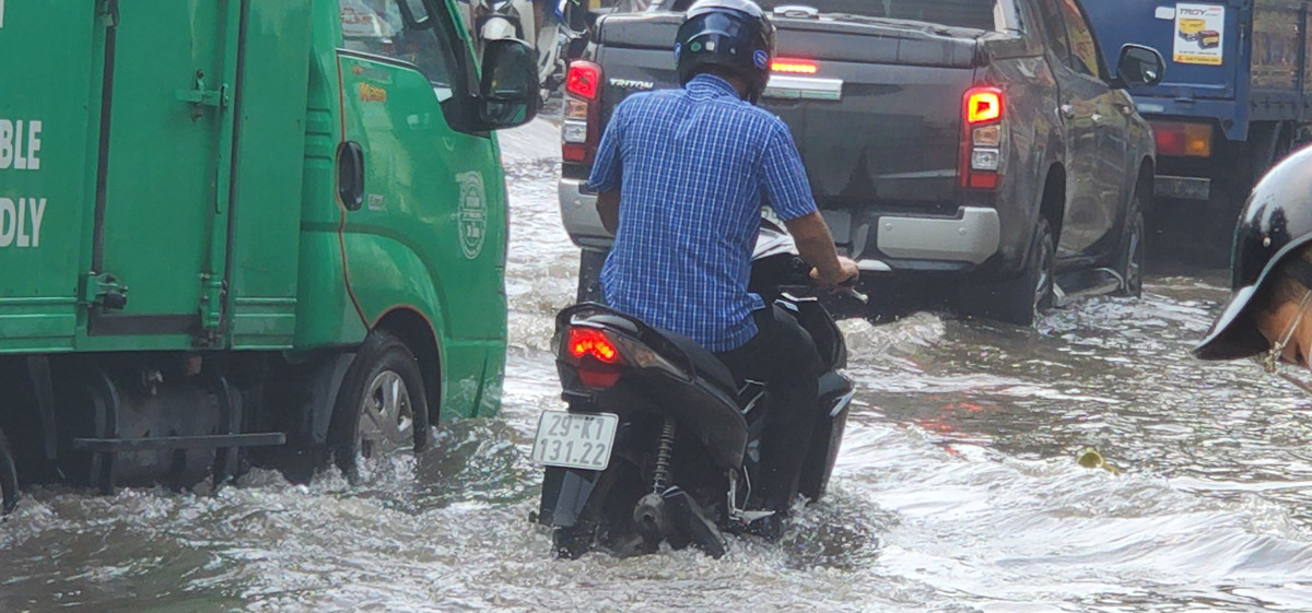 Nhiều người điều khiển xe máy vẫn cố tình di chuyển, bất chấp mực nước ngập sâu.