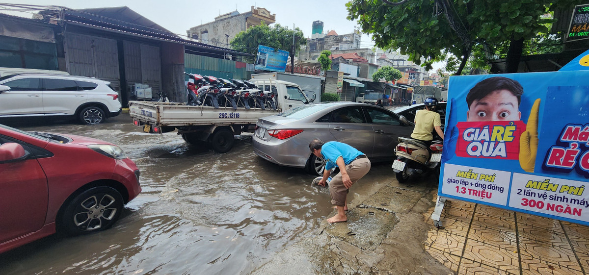 Mực nước ngập gần nửa bánh xe ô tô và tràn vào nhà dân hai bên đường.