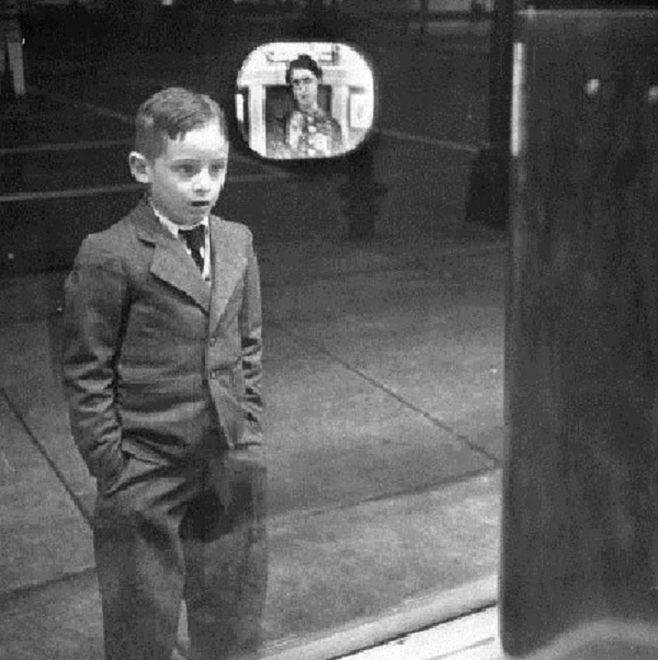 Một cậu bé đang chăm chú xem chương trình truyền hình từ một chiếc tivi đặt trong cửa hiệu năm 1948.