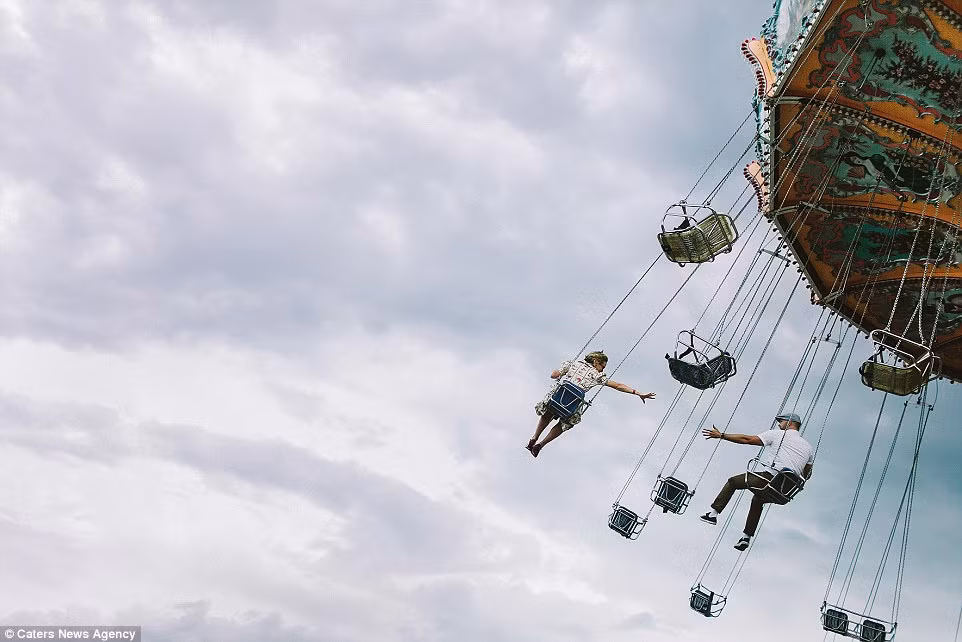 Cặp uyên ương cố gắng với tay nhau trong khi chơi đua quay trên cao.