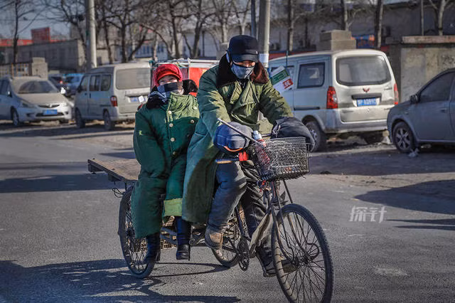 Gia đình một người lao động nghèo di chuyển trên chiếc xe đạp ba bánh.