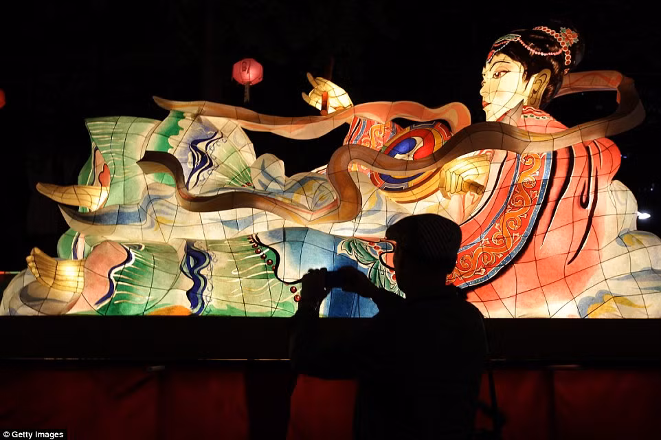 Một du khách chụp ảnh đèn lồng sáng rực rỡ trong đêm tại lễ hội đèn lồng Hoa sen. (Nguồn: Daily Mail)