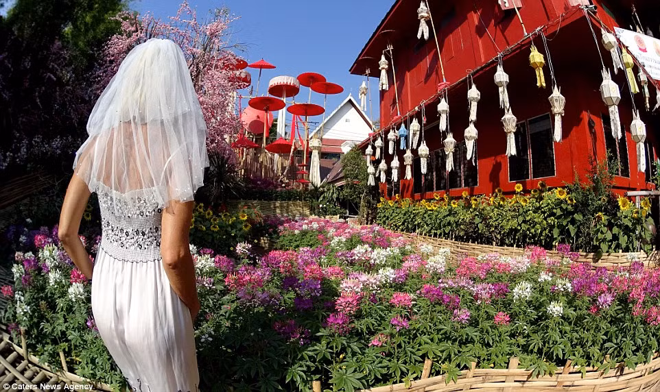 Cô mặc váy cưới chiêm ngưỡng vườn hoa rực rỡ trong một ngôi chùa ở Chang Mai, Thái Lan.