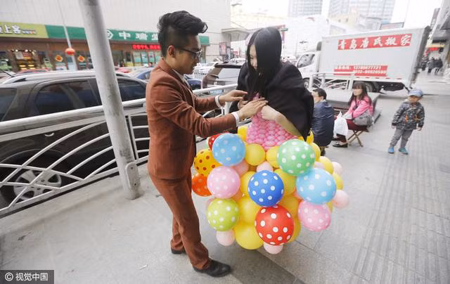 Một chiếc váy được thiết kế toàn bằng bóng bay màu trắng, trong khi chiếc váy còn lại có phần thân màu hồng và chân váy là những quả bóng chấm bi nhiều màu sắc.