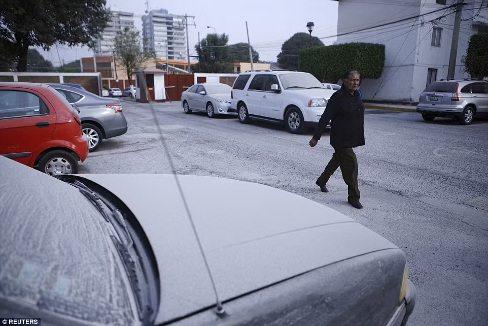 Người phụ nữ đi trên đường phủ đầy tro bụi núi lửa tại thành phố Puebla, Mexico. (Nguồn: Daily Mail)